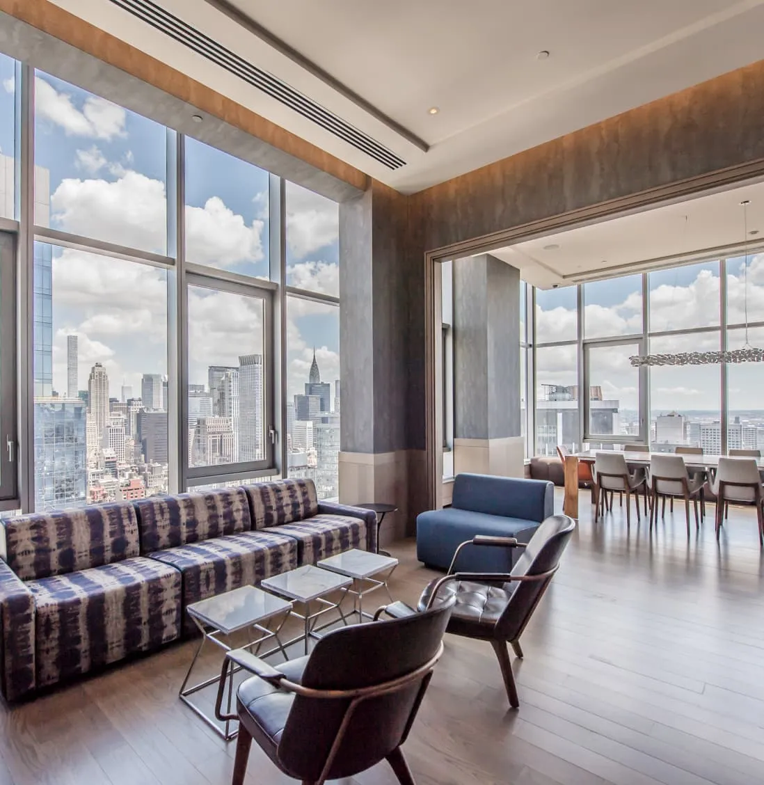 A spacious living area in EOS, featuring large windows that provide a panoramic view of the New York City skyline.